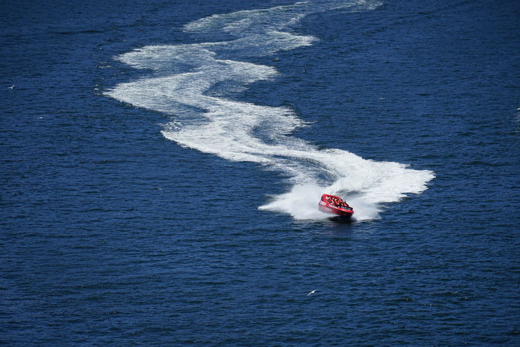 High angle view of boat in sea leaving a wavy trail of foam. a fast jet rippling down the water.