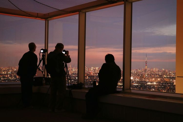 Silhouette men photographing tokyo sky tree in city during sunset