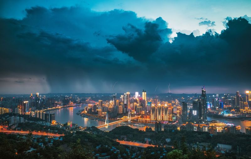 Aerial view of thunderstorm over illuminated buildings in city at night