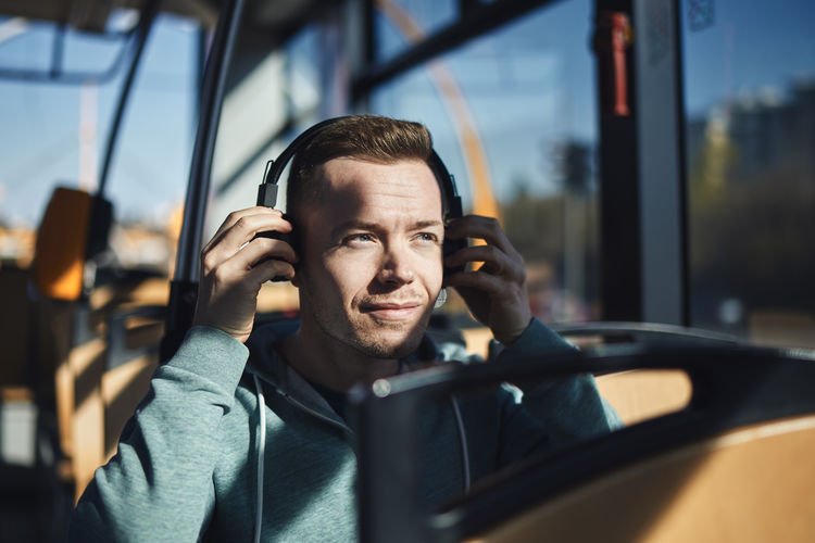 Man listening music in wireless headphones while commuting by public transportation.