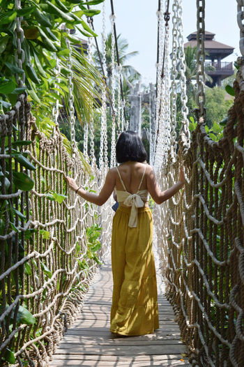 Rear view of woman walking on footbridge