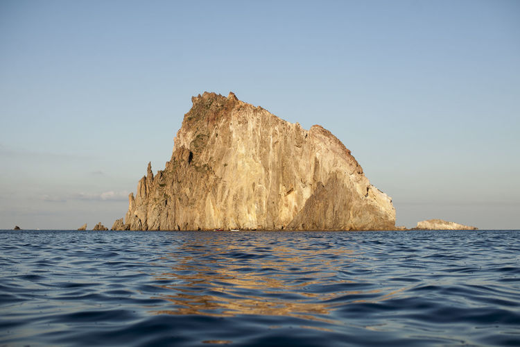 Rock formation in italian sea against clear blue sky