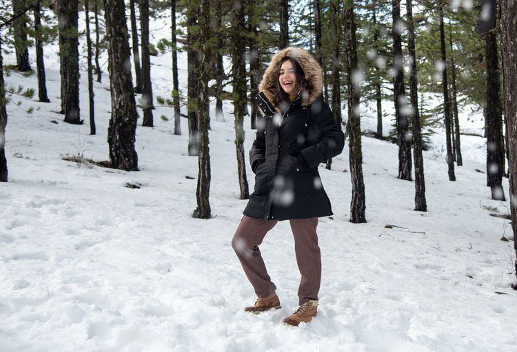 Full length portrait of woman standing on snow covered land