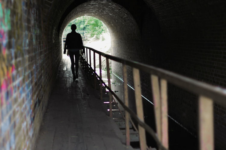 Silhouette man walking in tunnel