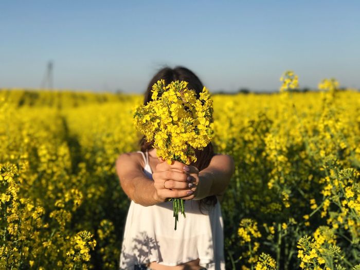 Woman holding yellow flowers in field