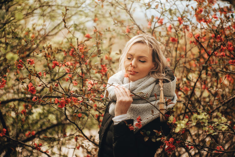 Portrait of beautiful young woman standing by tree in bloom