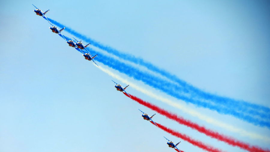 Low angle view of airplanes flying during airshow against sky