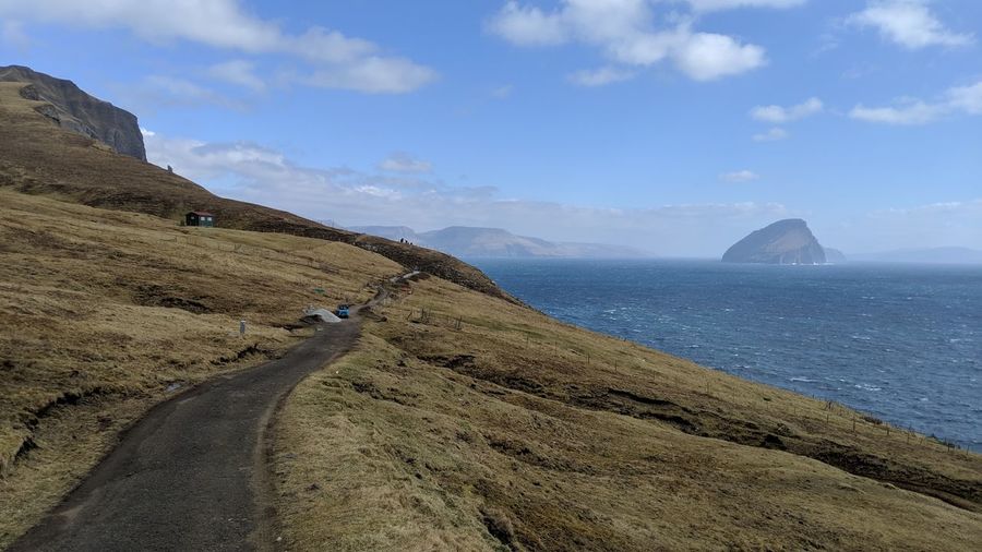 Scenic view of road by sea against sky