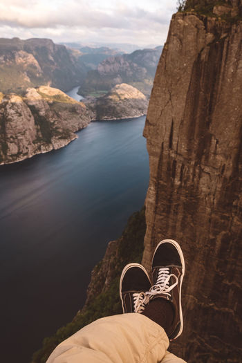 Person cross legged at edge of cliff with a fjords view in norway