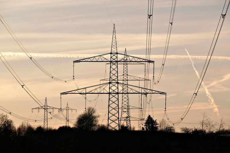 Low angle view of silhouette electricity pylon against sky during sunset