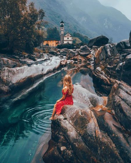 Woman sitting on rock by mountain