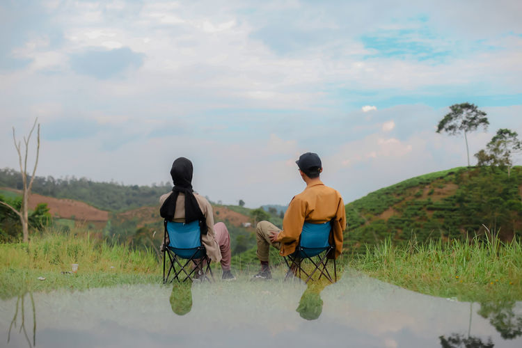 Rear view of couple walking on road against sky
