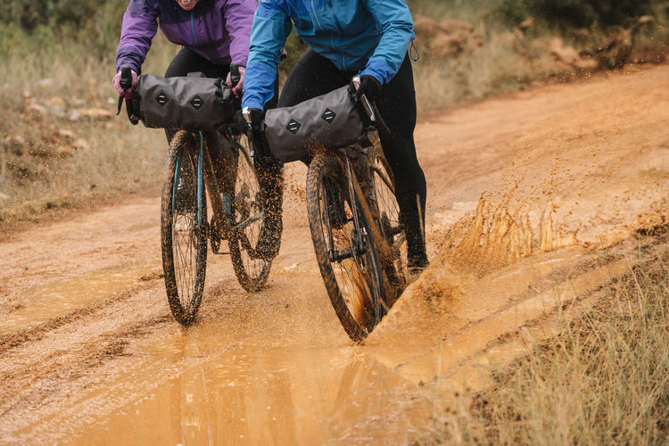People in protective helmet and colorful jacket riding bikes in forest during bike packing adventure