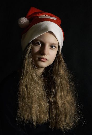 Portrait of beautiful young woman against black background
