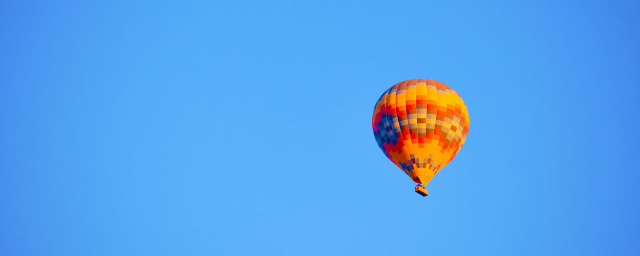 Low angle view of hot air balloons against clear blue sky