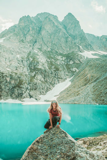 Woman sitting on rock by mountain