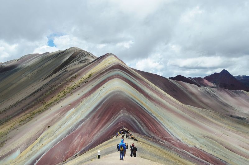 People on multi colored mountain against sky