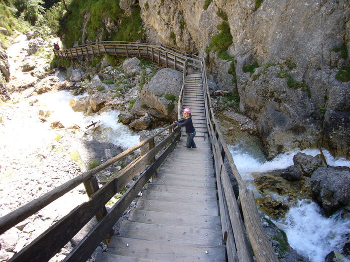 High angle view of girl standing on bridge over stream against mountains