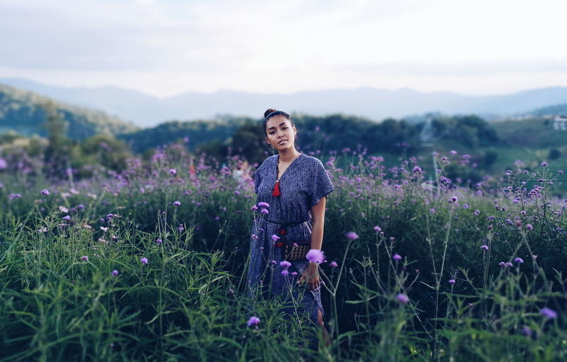 Woman standing amidst plants on field against sky