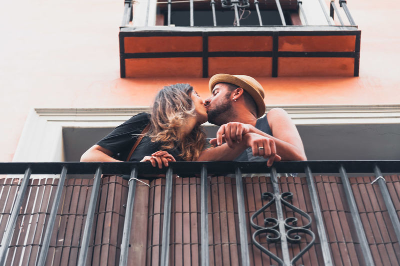 Low angle view of young couple kissing at balcony