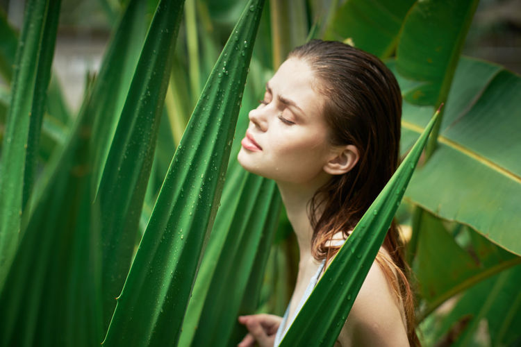 Young woman looking away against plants