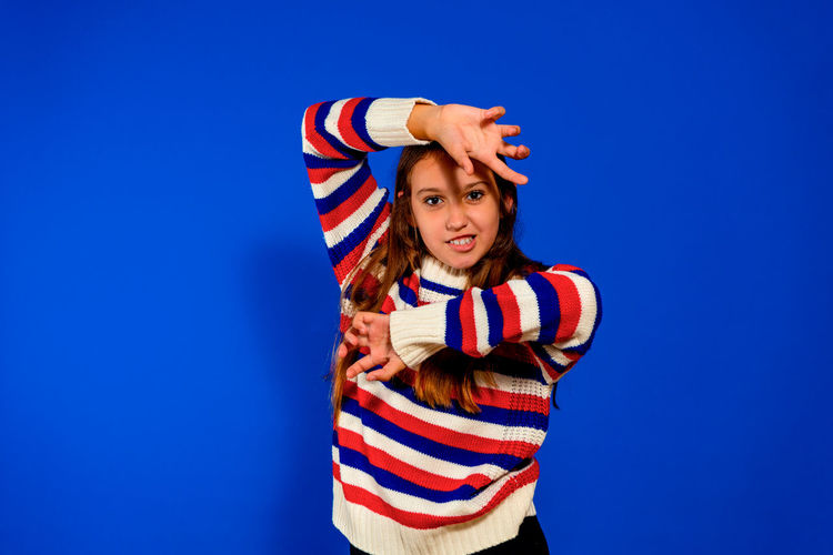 Portrait of girl standing against blue background