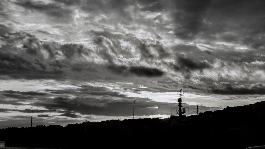 Silhouette of electricity pylon against dramatic sky