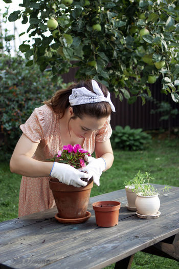 A woman replants an impatiens in a new pot