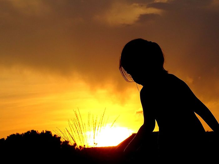 Silhouette woman against orange sky during sunset
