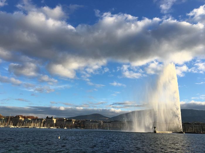 Fountain in city by sea against sky