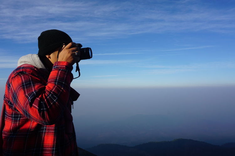 Man photographing against blue sky
