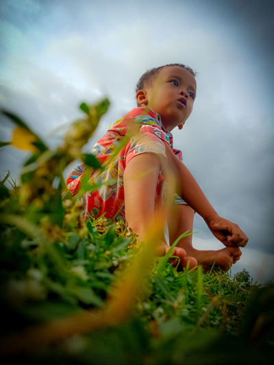 Girl looking away while standing on land against sky