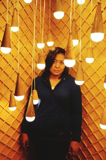 Portrait of young woman standing in illuminated room
