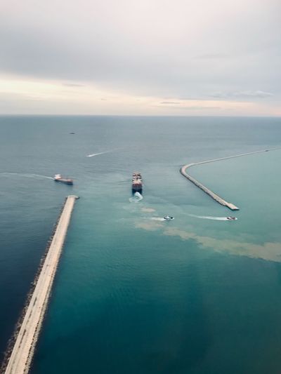 Aerial view of nautical vessels in sea by pier against sky