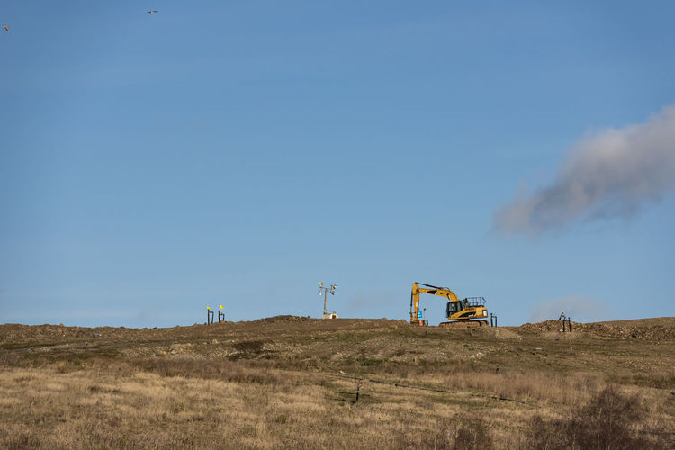 Wind turbines on field against blue sky