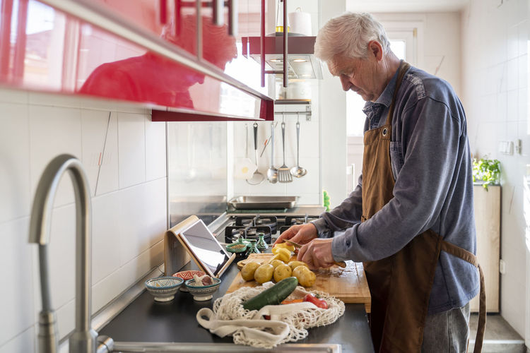 Side view of man preparing food in kitchen at home