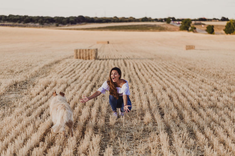 Mid adult woman with dog on agricultural field