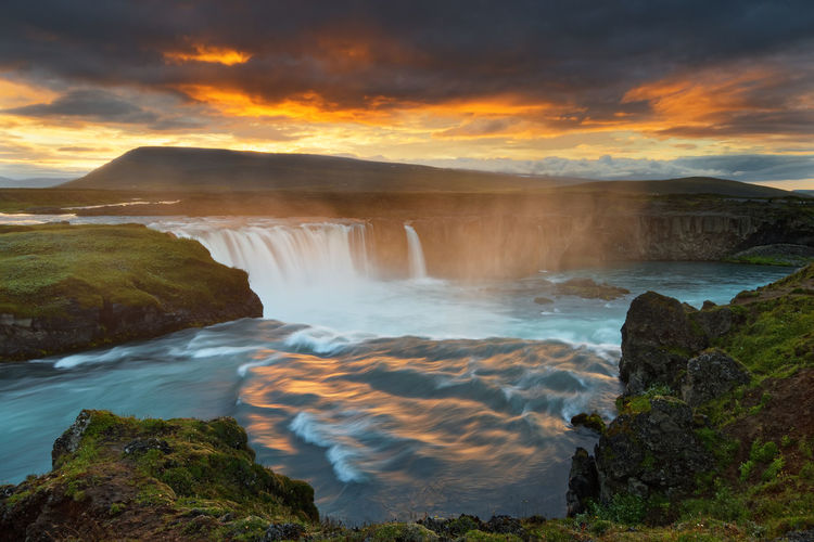 Scenic view of waterfall against sky during sunset