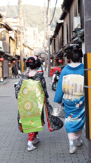 Rear view of women walking on street in city