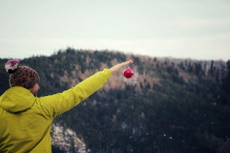 Rear view of man holding bauble against mountain