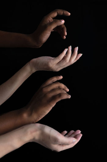 Cropped hands of multi-ethnic people against black background