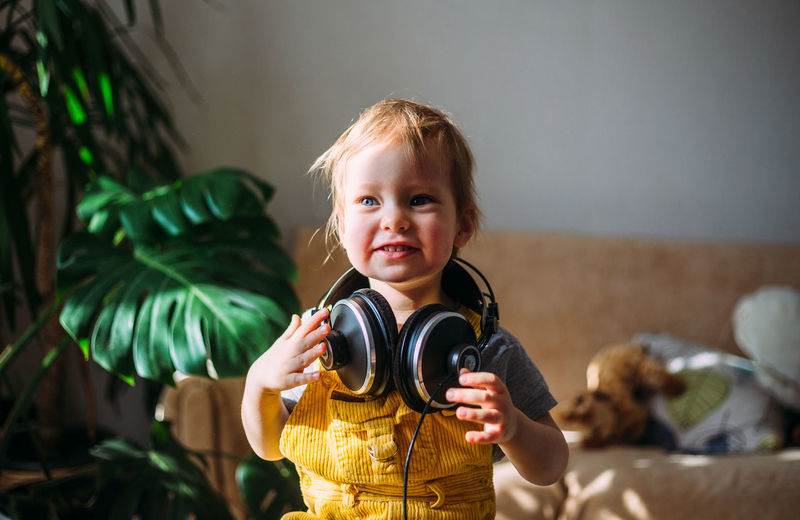 Funny little child having fun with headphones at home, portrait.