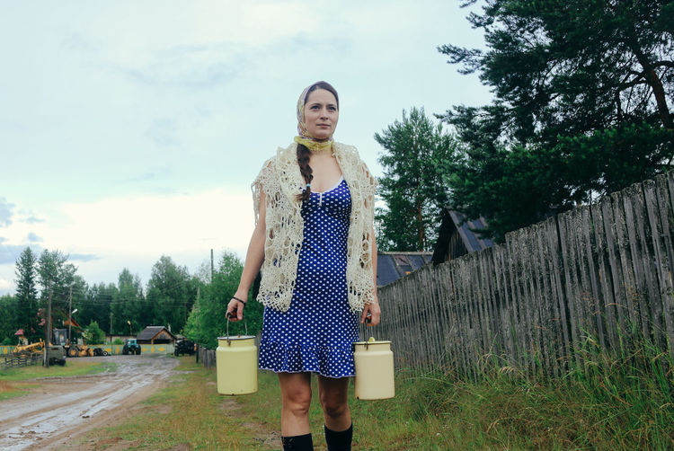 Rustic young woman in blue polka dot dress with cans