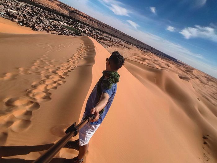 Man on sand at desert against sky