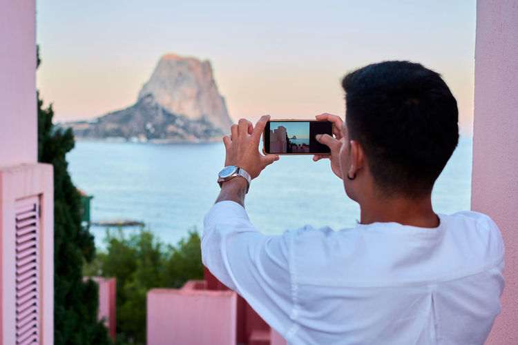 Young latin man takes a photo with his mobile