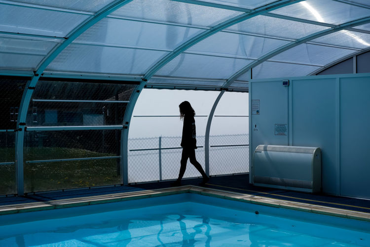 Side view of woman standing by swimming pool
