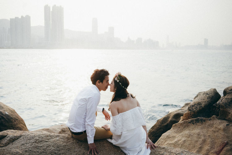 Couple sitting by sea on rocks