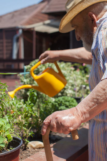 Midsection of senior man watering plant