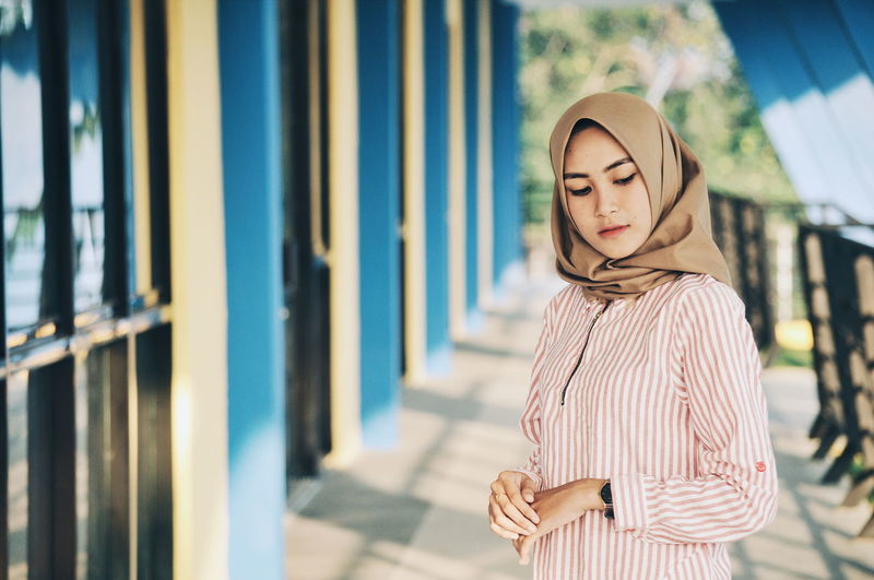 Woman wearing hijab while standing on corridor
