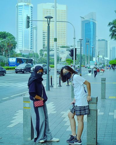 Rear view of women standing on street in city